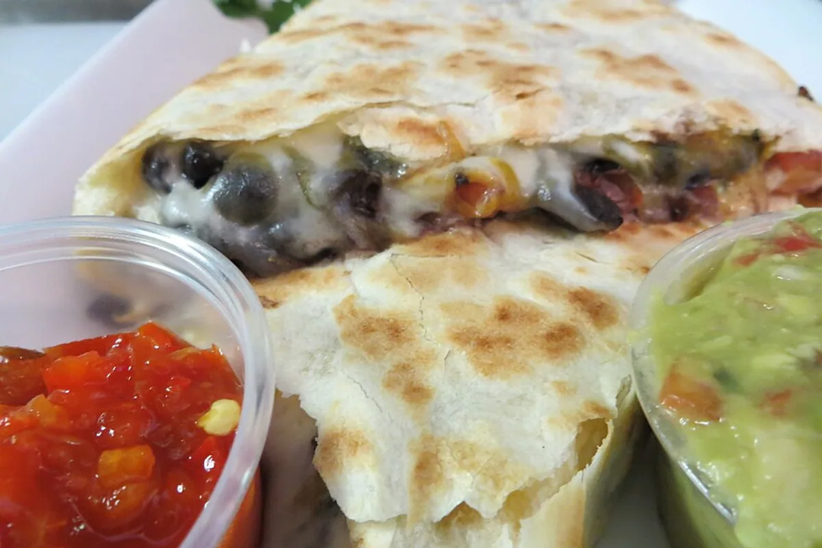 Toasted black bean quesadilla with peppers melted cheese salsa and guacamole