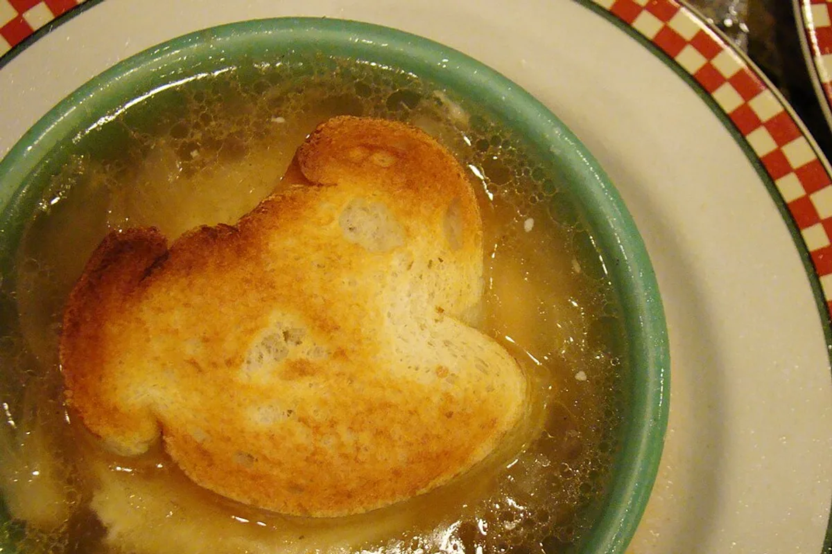 Clear French onion soup with deeply browned onions and two pieces of toast