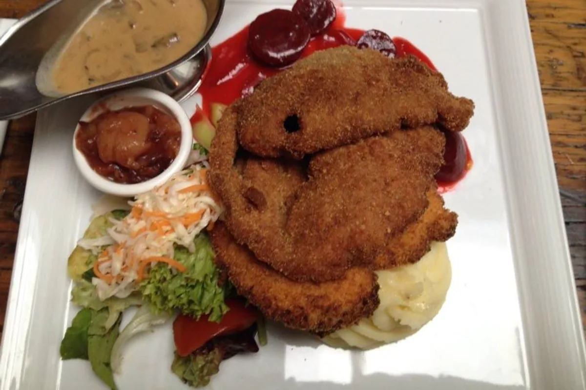 Golden breaded pork schnitzel with onion rings mashed potatoes and salad