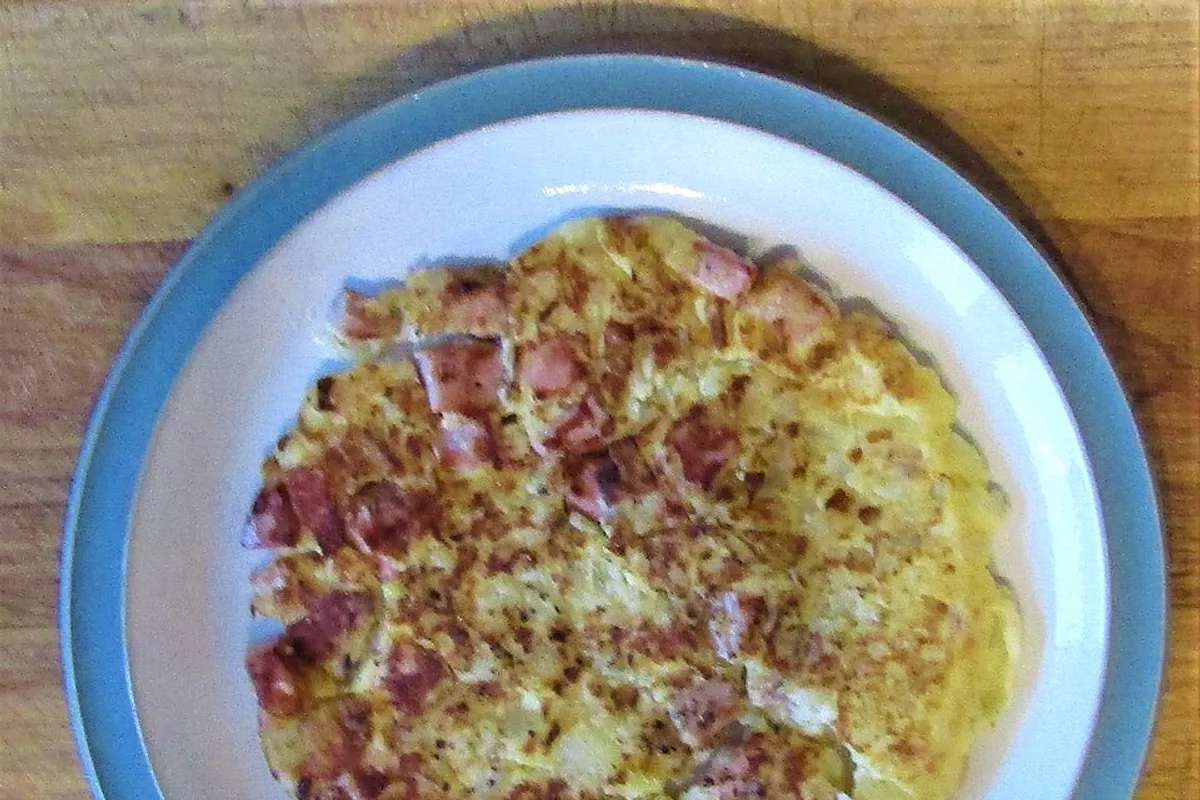 Thick potato ham and onion Spanish tortilla on a white plate