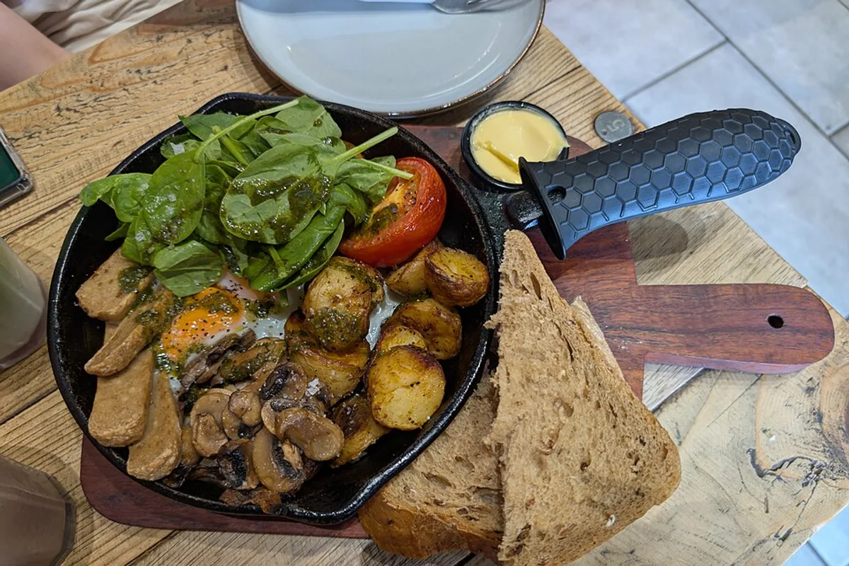 Breakfast skillet with potatoes vegetarian sausages eggs mushrooms spinach tomato and toast