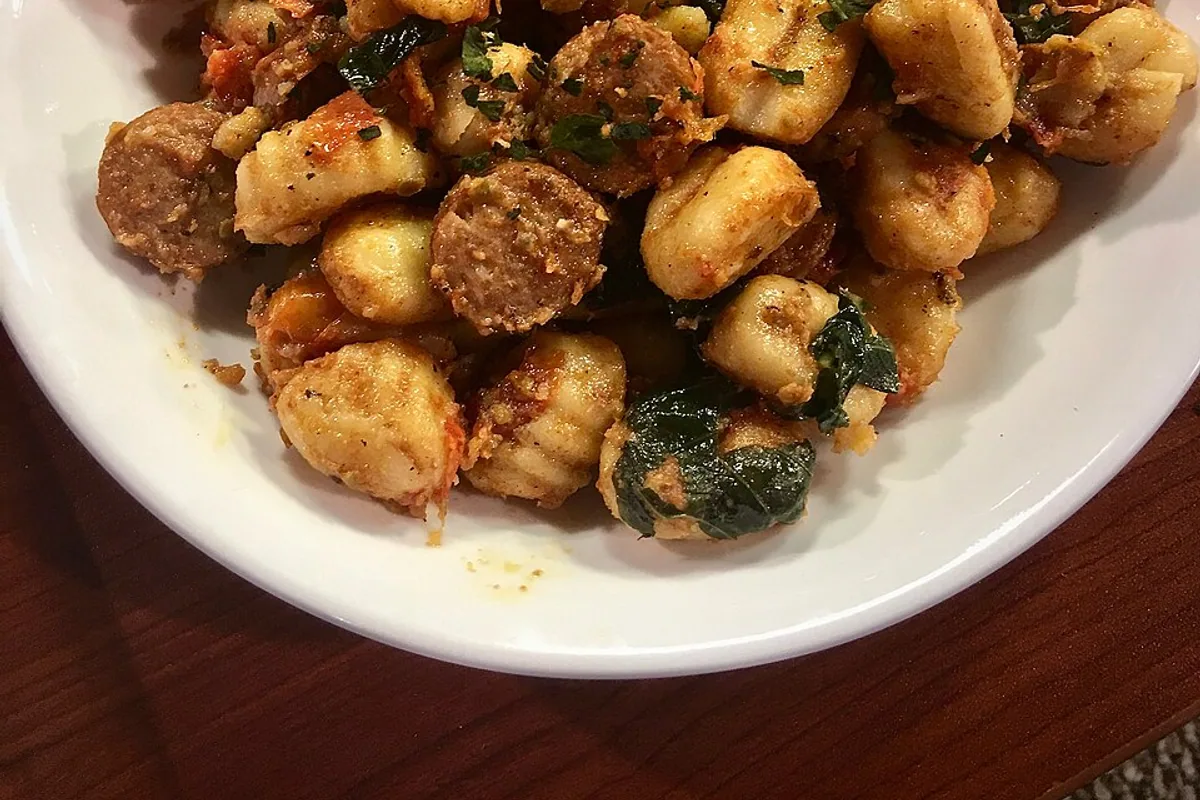 Golden gnocchi with chicken sausage tomatoes and greens